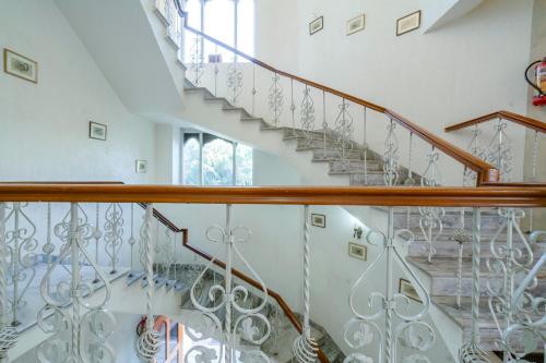 a staircase in a home with white walls and wooden railings at Hotel Chandrawati Palace in Ābu Road