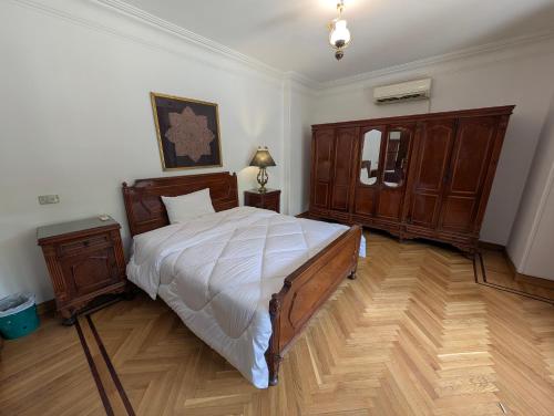 a bedroom with a large bed and wooden furniture at Villa Maadi - 35 - R 1 Street view Room in Cairo