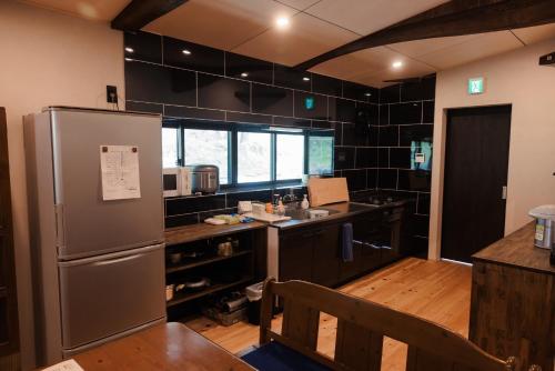 a kitchen with a stainless steel refrigerator and a counter at 古民家一棟貸し有山 in Nakatsugawa