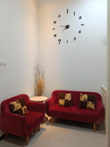 a living room with two red couches and a clock on the wall at VILLA BATU 3F in Batu