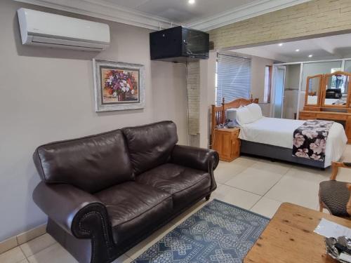 a living room with a leather couch and a bed at La Cordier in Kroonstad