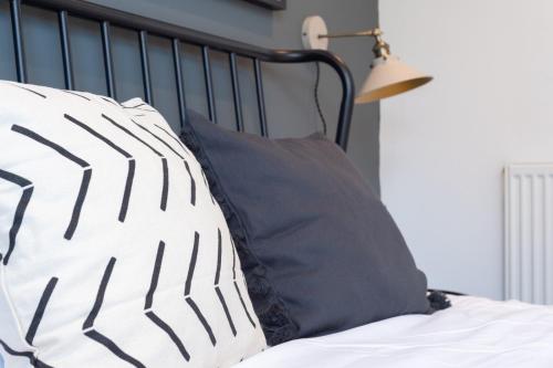a bed with black and white pillows and a lamp at Bridge House Apartments - Free Parking in Shottery