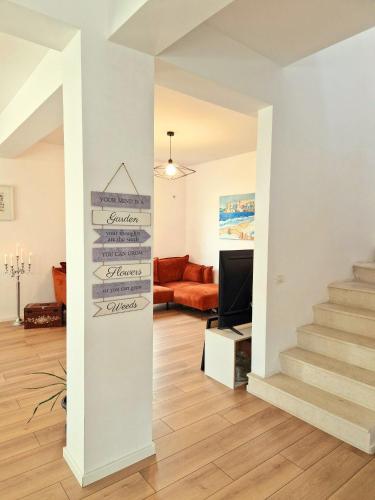 a living room with stairs and a sign that reads home sweet home at Dalia-Serenity next to Therme in Baloteşti