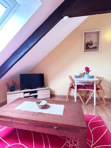 un salon avec une table et une télévision dans l'établissement Au fil du temps, à Morlaix