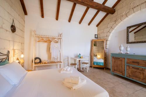 a bedroom with a white bed and a table at Agriturismo Alonì Costarella Masseria in Borgagne