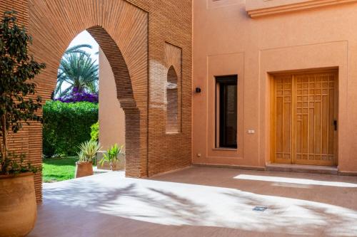 een boog die leidt naar een gebouw met een deur bij Villa les Palmiers in Marrakesh