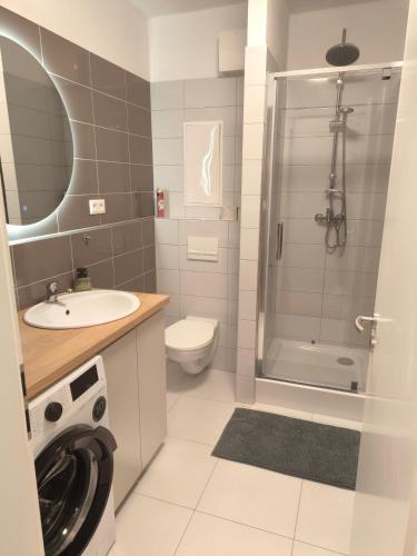 a bathroom with a shower toilet sink and a washing machine at modern apartment in Senica