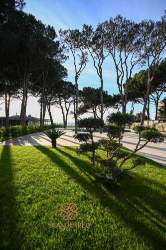 a shadow of trees on the grass near a sidewalk at Hotel Skanderbeg in Golem