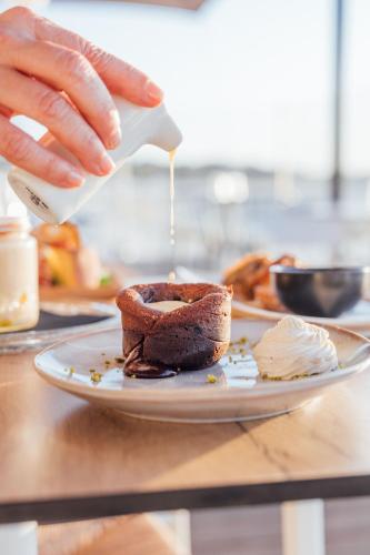 a person is pouring peanut butter on a piece of bread at Beach Hotel - Le Grand Chalet in Ronce-les-Bains