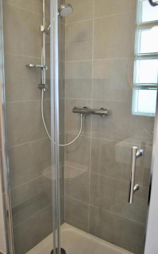 une douche avec une porte vitrée dans une salle de bain dans l'établissement Villers very center, sea view - Private parking, à Villers-sur-Mer