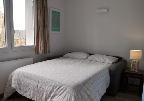- une chambre avec un lit doté d'une couverture blanche et d'une fenêtre dans l'établissement Villers very center, sea view - Private parking, à Villers-sur-Mer