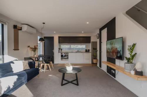 a living room with a blue couch and a table at Travellers' dream steps from shops and close to Airport in Christchurch