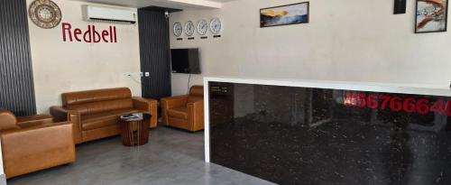 a waiting room with leather chairs and a tv at Redbell Suites Civil in Kozhikode