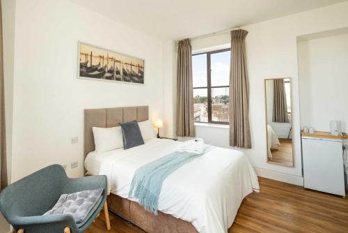 a bedroom with a bed and a chair and a window at London City Hotel in Woolwich