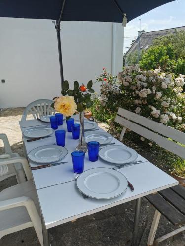 une table blanche avec des assiettes et des fleurs bleues sur elle dans l'établissement Maison familiale La Cachottiere, à Arradon
