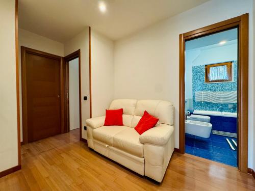YourHome - A Casa di Manuela في سانتّانييلّو: غرفة معيشة مع أريكة بيضاء مع وسادتين حمراء