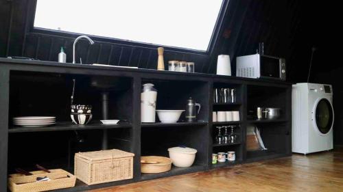 a black shelf with dishes and a microwave at The ZenDen in Lindula