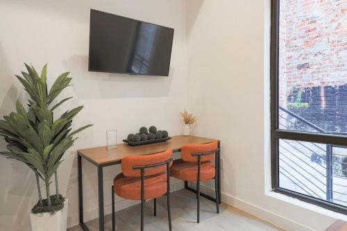 a dining room table with orange chairs and a tv on a wall at Unit 5 Cozy 1 Bed Room with Queen Bed plus Sofa Pullout in Washington, D.C.