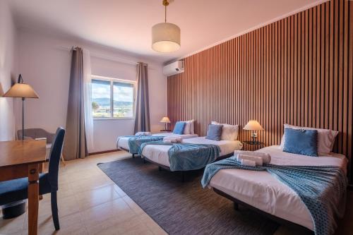 a hotel room with three beds and a desk at Casa Areal de Santa Barbara in Ribeira Grande