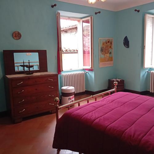 a bedroom with a bed and a dresser and two windows at Casa 28 Luglio - Appartamento in Mercatello sul Metauro