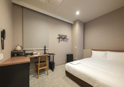 a bedroom with a bed and a desk and a bed and a desk at Hotel Reference Kokuraekimae in Kitakyushu