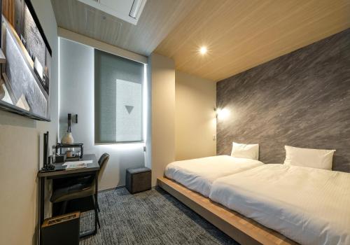 a bedroom with a bed and a desk and a window at Hotel Reference Kokuraekimae in Kitakyushu