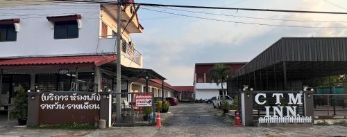 Una calle con un edificio con letreros. en CTM.INN (SISAKET)THAILAND, en Ban Bua Toei