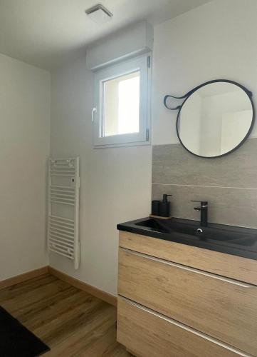une salle de bain avec un lavabo et un miroir au mur dans l'établissement Maison spacieuse à Saint-Brevin, près de la mer, à Saint-Brévin-les-Pins