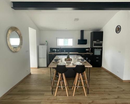 une cuisine avec une table et des tabourets dans une pièce dans l'établissement Maison spacieuse à Saint-Brevin, près de la mer, à Saint-Brévin-les-Pins