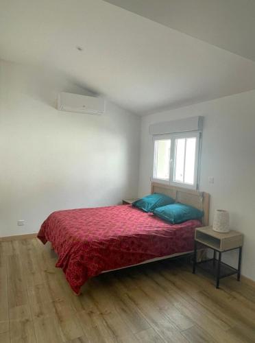 une chambre avec un lit avec une couverture rouge et une fenêtre dans l'établissement Maison spacieuse à Saint-Brevin, près de la mer, à Saint-Brévin-les-Pins