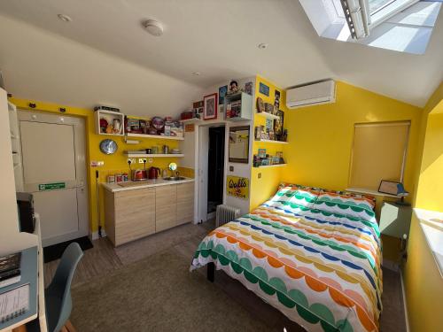 a bedroom with a bed and a kitchen with yellow walls at Cherry Cottage Retro Stay, Stourport-on-Severn in Stourport