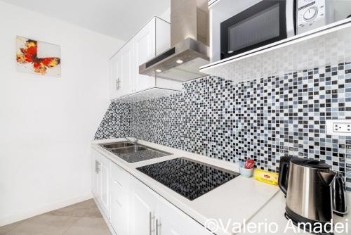 a kitchen with a sink and a black and white tiled wall at KB Apartments Karon Beach by PHR in Karon Beach