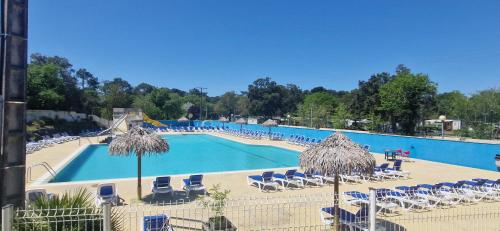 a large swimming pool with chairs and umbrellas at Cosy mobil home 3Ch en forêt, parking inclus, plage à 15mn à pied in Capbreton