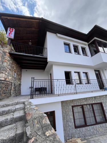 a white house with a balcony and a stone wall at Hotel Berati in Prizren