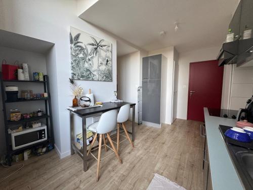 une cuisine avec une table et deux chaises blanches dans l'établissement Charmant duplex cosy au centre ville, à Périgueux