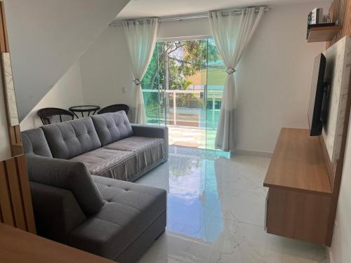 a living room with a couch and a television at Luxo com Spa exclusivo no paraíso do Peró! in Cabo Frio