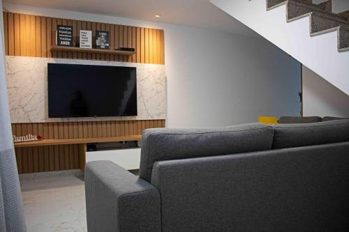 a living room with a couch and a flat screen tv at Luxo com Spa exclusivo no paraíso do Peró! in Cabo Frio