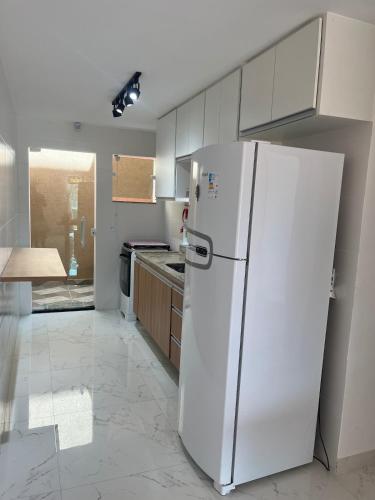 a kitchen with a white refrigerator in a room at Luxo com Spa exclusivo no paraíso do Peró! in Cabo Frio