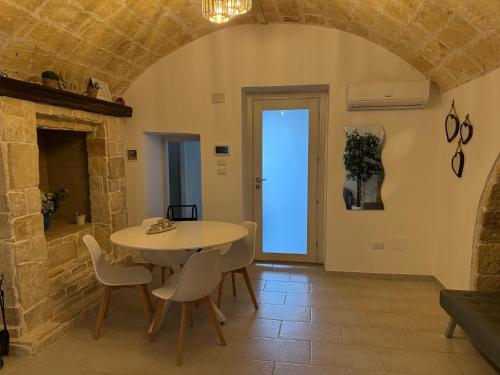 comedor con mesa, sillas y pared de piedra en Casa Angel, en Mesagne
