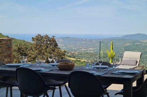 - une table en bois avec des verres à vin et des chaises sur la terrasse dans l'établissement Villa climatisée vue mer piscine privée chauffée wifi 810 personnes, à Sollacaro