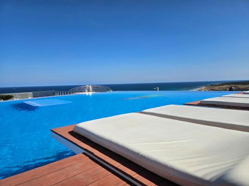 two beds on a deck with the ocean in the background at INFINITY View Amazing Beachfront Apartment in Arenales del Sol