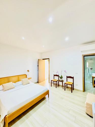 a white bedroom with a large bed and chairs at CASA SACURI in Rudalza