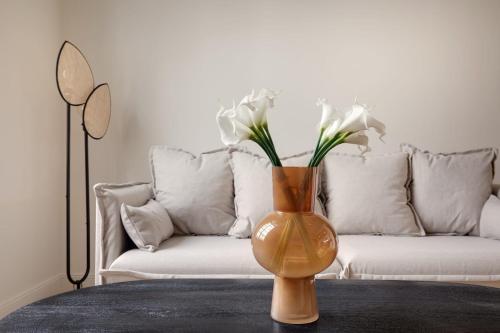 un vase avec des fleurs blanches sur une table devant un canapé dans l'établissement Appartement Place de Gaulle - Welkeys, à Antibes