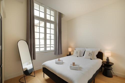 - une chambre dotée d'un grand lit blanc avec deux bougies dans l'établissement Appartement Place de Gaulle - Welkeys, à Antibes