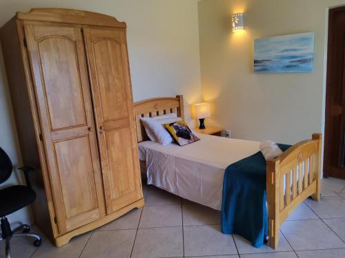 a bedroom with a bed and a wooden cabinet at Monks Hill Villa in Falmouth