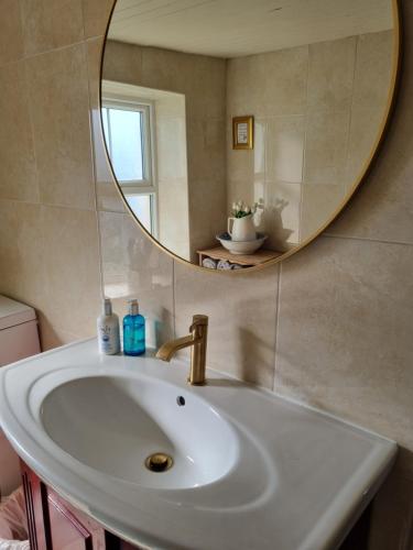 a bathroom with a sink and a round mirror at The Lodge at Heathfield House in Ballycastle