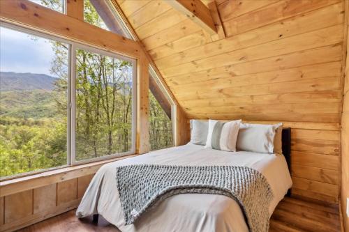 a bedroom with a bed in a room with windows at Dog Friendly, Hot Tub, Game Room, Ev Charger in Gatlinburg
