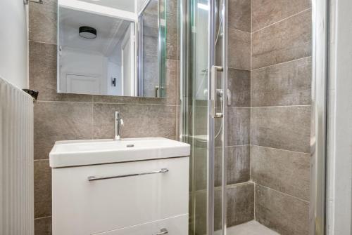 une salle de bain avec un lavabo blanc et une douche dans l'établissement One bedroom apartment with its modern decor - CheckProfile, à Levallois-Perret