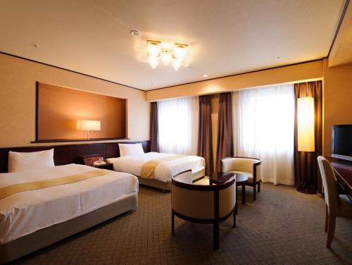 una camera d'albergo con due letti e una televisione di Chisun Hotel Utsunomiya a Utsunomiya