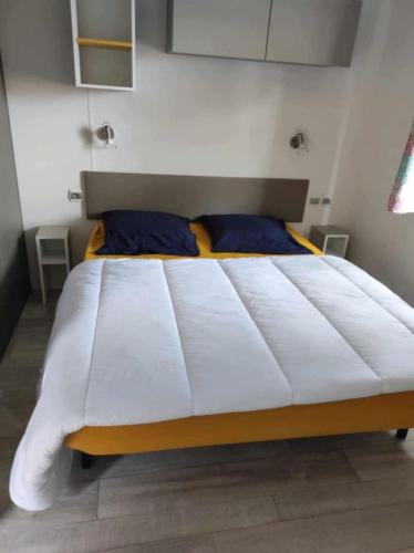 - un grand lit blanc dans une chambre avec des oreillers bleus dans l'établissement Mobil home Camping La Marine, au Grau-du-Roi